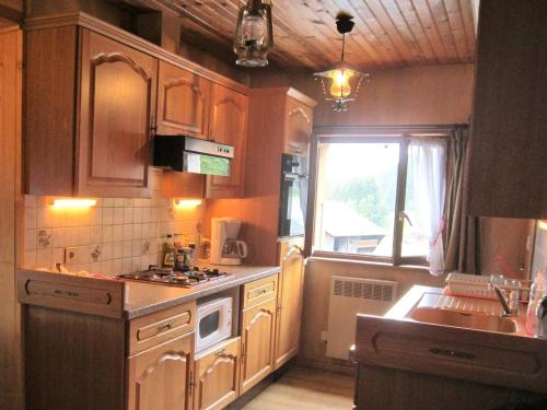 une cuisine avec des armoires en bois, un évier et une fenêtre dans l'établissement Les Gets - Appartement 3 Pièces - 7 Pers - 100m Télésiège - Wifi - Parking - FR-1-802-85, aux Gets