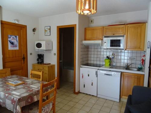une cuisine avec des appareils électroménagers blancs et une table avec une nappe dans l'établissement Les Gets: 2P 4 Pers, WiFi, Terrasse Sud, 250m des Commerces - FR-1-802-86, aux Gets