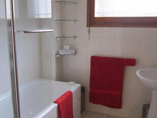 La salle de bains est pourvue d'une baignoire, d'un lavabo et d'une serviette rouge. dans l'établissement Appartement 3 pièces - 6 pers - Terrasse, Garage, Wi-Fi - Proche Pistes - Les Gets - FR-1-802-66, aux Gets