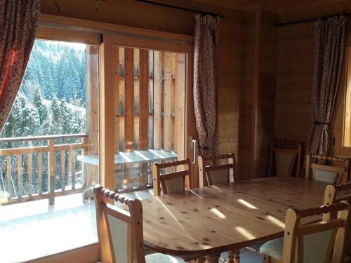 une salle à manger avec une table et une grande fenêtre dans l'établissement Chalet familial aux Gets, 8 pers, 150m des pistes, 4 chambres, 4 SDB, terrasse sud, proche lac - FR-1-802-71, aux Gets