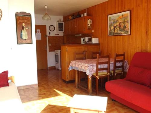 un salon avec une table et un canapé rouge dans l'établissement Location Studio Les Gets - 4 pers - Centre, parking, au calme - FR-1-802-77, aux Gets