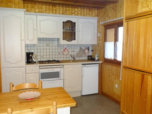 une cuisine avec des armoires blanches et une table en bois dans l'établissement Appartement rénové 2 pièces pour 4 personnes aux Gets, proche pistes, parking et WiFi inclus - FR-1-802-91, aux Gets
