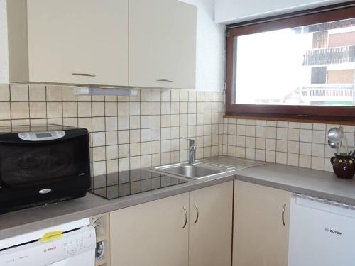 une cuisine avec un évier et un micro-ondes dans l'établissement Charmant T2 lumineux pour 5 pers, 300m des commerces, avec balcon et box à skis - Les Gets - FR-1-802-81, aux Gets