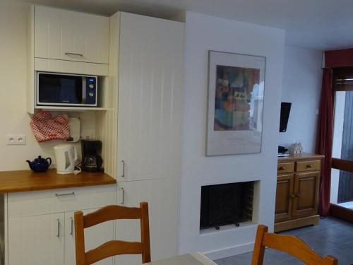 une cuisine avec des placards blancs et un comptoir avec une cheminée dans l'établissement Les Gets - 3 Pièces Confort - 6 Pers - Arrivée Skis - WIFI - 250m Commerces - FR-1-802-89, aux Gets