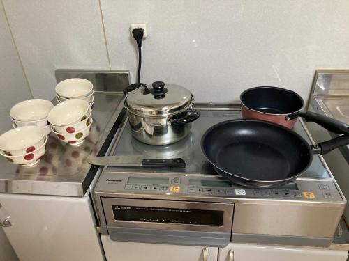 a frying pan on a stove with pots and pans at 寺田旅館一軒家レンタル素泊まり最大15人宿泊可能 4名様まで同一料金 in Mine