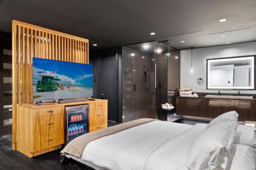 a bedroom with a bed and a tv and a bathroom at Modern City Loft in Downtown River District in Fort Myers