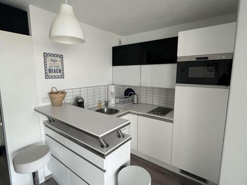 une petite cuisine avec des armoires blanches et un évier dans l'établissement Appartement T2 climatisé à 200m plage, terrasse, parking, 4 couchages - La Grande-Motte - FR-1-250-291, à La Grande Motte