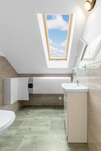 a bathroom with a toilet sink and a window at Domki Niedźwiadki nad morzem in Kopalino