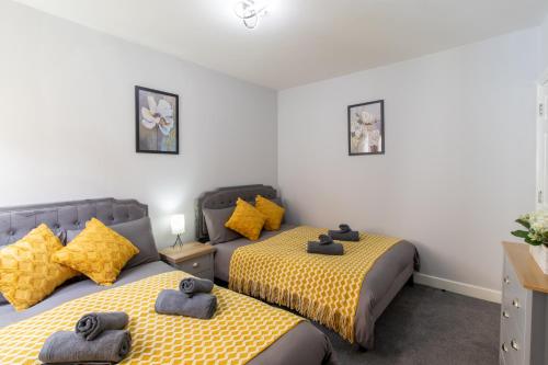 two beds in a room with yellow and black sheets at Open Mind Property - Cosy Apartment with 3 Beds in Portsmouth