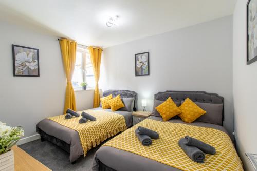 a bedroom with two beds with gray and yellow sheets at Open Mind Property - Cosy Apartment with 3 Beds in Portsmouth