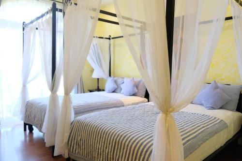 a bedroom with two beds with white drapes at La Marina Boutique Hotel & Spa in Mui Ne