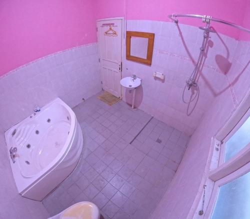 a pink bathroom with a toilet and a sink at Villa Taman Damai in Beran-kidul