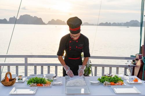 a man preparing food on a table on a boat at Halong Arcadia Cruise in Ha Long