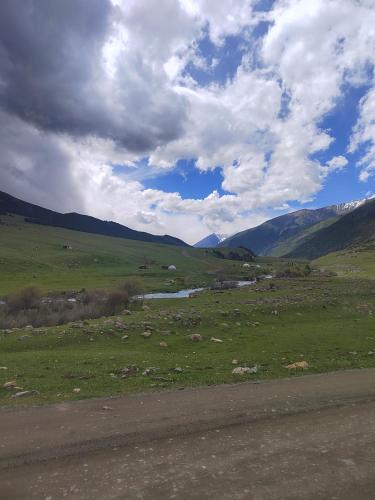 a green field with a river and mountains in the background at У Дяди Жени in Temirovka