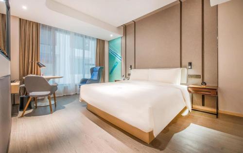 a hotel room with a large white bed and a desk at Atour Hotel Guangzhou Sanyuanli-Guangzhou Baiyun Railway-Fiee Self-Service Laundry in Guangzhou