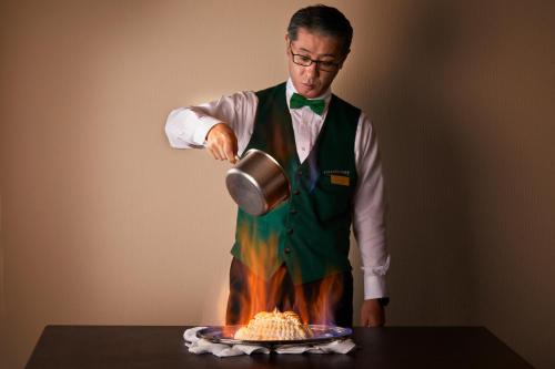 a man standing in front of a cake with a pot at Hotel Continental Fuchu in Fuchu