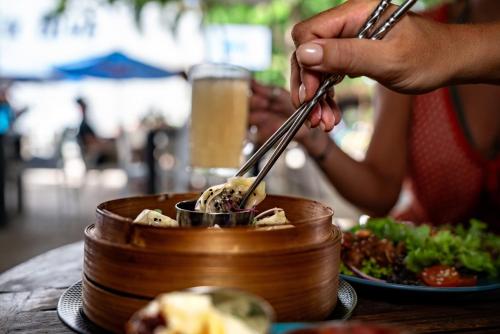 a person is eating food in a bowl with tongs at Manta Dive Gili Trawangan Resort in Gili Trawangan
