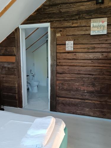 a bathroom with a wooden wall and a toilet at Farm Stay Agroturism Bori Punct Gastronomic Local in Gura Humorului