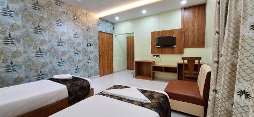 a room with two beds and a desk and a television at New Sun International & Banquet Hall in Jamshedpur