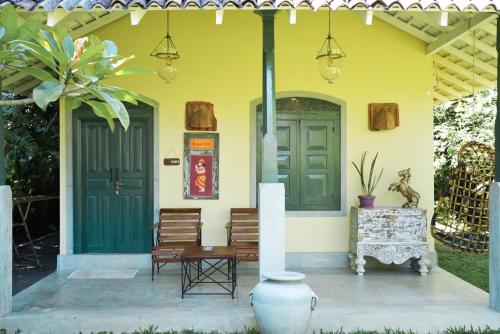 a yellow house with a green door and chairs at Villa Hillcrest in Weligama