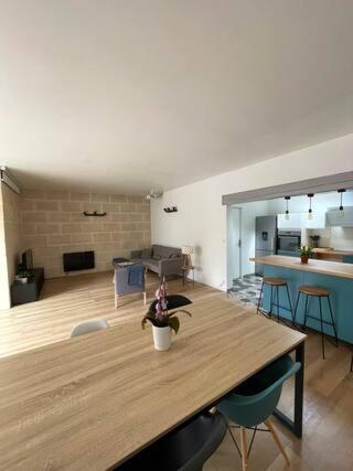 a living room with a wooden table and a kitchen at Maison de ville paisible in Lormont
