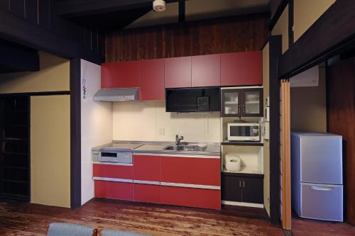 a kitchen with red cabinets and a sink and a refrigerator at Heiankyu-dairi no yado in Kyoto