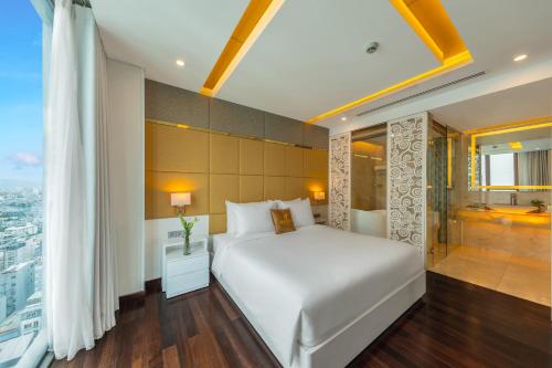 a bedroom with a white bed and a shower at Mandila Beach Hotel Danang in Da Nang