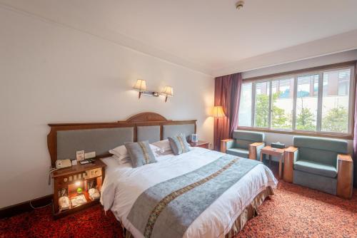a bedroom with a bed and a couch and a window at E-mei Mountain Hotel in Emeishan