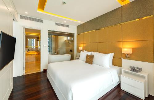 a bedroom with a large white bed and a television at Mandila Beach Hotel Danang in Da Nang