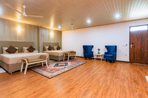a bedroom with two beds and two blue chairs at Beach & Bliss Mirissa in Mirissa
