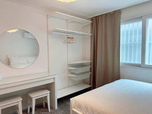 a bedroom with a bed and a dressing table and a mirror at Sophie House foreigners women only in Seoul