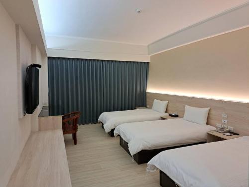 a hotel room with two beds and a flat screen tv at Etung Hotel in Taichung
