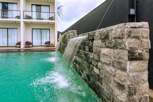 a waterfall in a stone wall next to a swimming pool at Beach & Bliss Mirissa in Mirissa