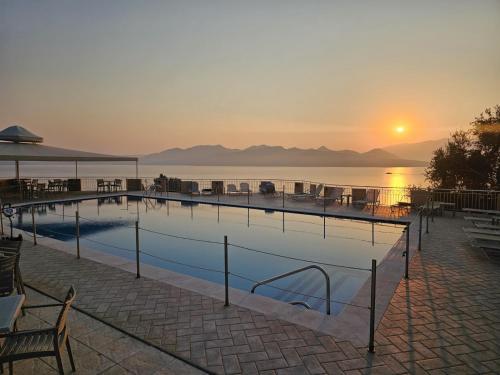 a swimming pool with the sun setting over the water at Sunrise Hotel Nikiana Lefkada in Nikiana