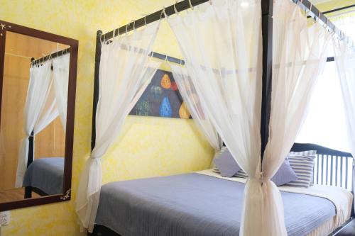 a bedroom with a canopy bed and a mirror at La Marina Boutique Hotel & Spa in Mui Ne