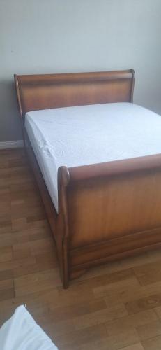 - un lit avec un cadre en bois sur du parquet dans l'établissement Appartement 3 chambres 6 personnes - Madeleine Tram B Dunoise, à Saint-Jean-de-la-Ruelle