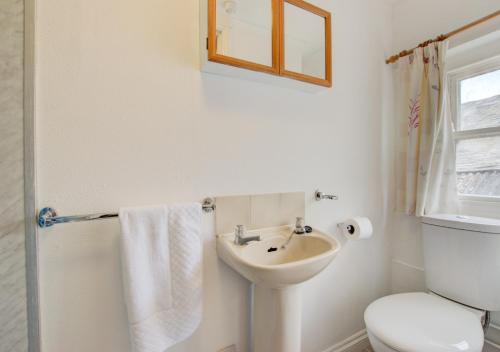 a white bathroom with a sink and a toilet at 1 Copper Kettle Apartment in St Ives