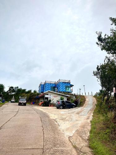 a blue house on the side of a dirt road at The Moon House บ้านพักภูทับเบิก Phu Thap Buek in Ban Maeo Thap Boek