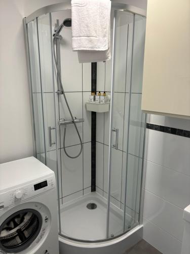a shower in a bathroom with a washing machine at Apartament Street Art ZASPA - wśród murali in Gdańsk