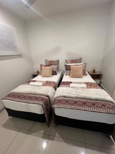 two beds sitting next to each other in a room at Darwin City Retreat 2 bedrooms in Darwin