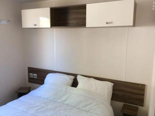 une chambre avec un lit avec des draps blancs et des oreillers dans l'établissement Confortable bungalow proche de Vias avec piscine partagée, à Vias