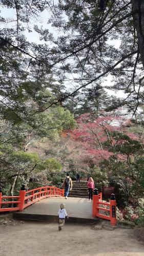 a young child crossing a bridge over a orange bridge at ガーデンリゾート 潮美庵 in Hatsukaichi