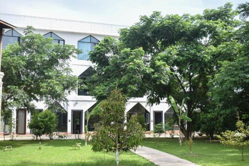 a white building with trees in front of it at Vangvieng Lina hotel in Vang Vieng