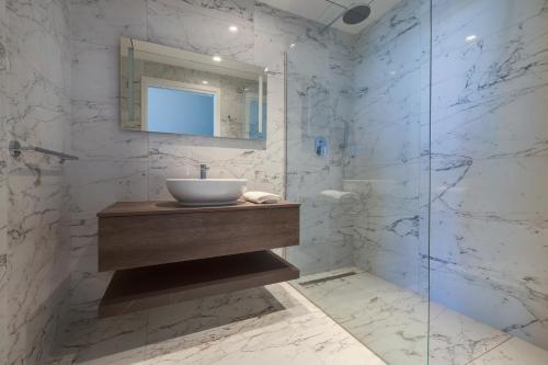 a bathroom with a sink and a glass shower at Mercury Tower Apartments in St Julian's
