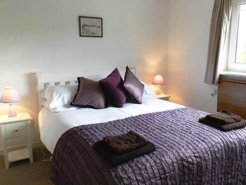 a bedroom with a large bed with purple pillows at Hartholm in Brodick