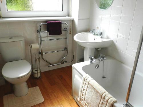 a bathroom with a toilet and a sink and a bath tub at Hartholm in Brodick
