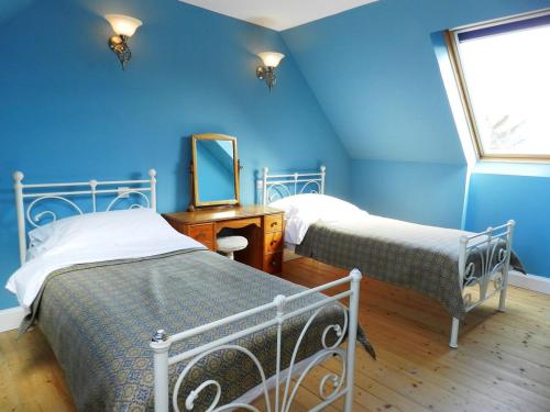 a blue bedroom with two beds and a mirror at Castleside Croft in Kildonan