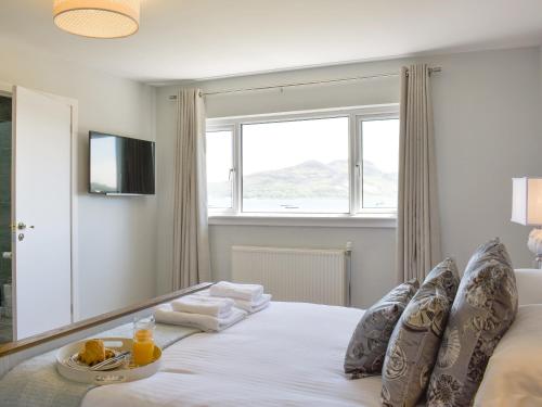 a bedroom with a large white bed with a window at Kinneil Land in Lamlash