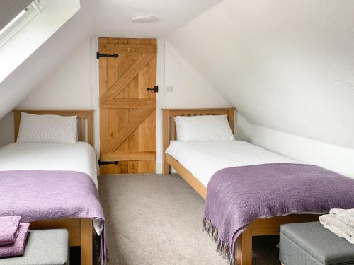 two beds in a room with a barn door at Woodlea Cottage 2 in Dippin