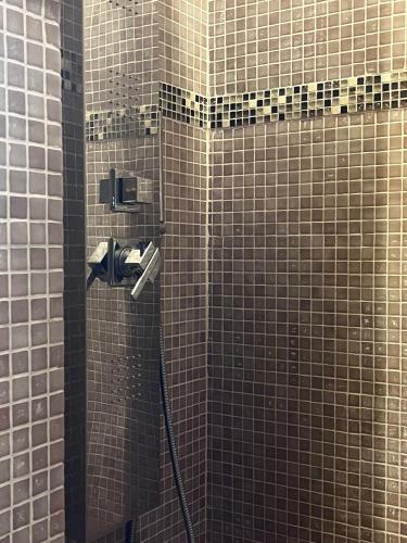 a bathroom with a shower with brown tiled walls at Hotel Holiday Debili in Sauze dʼOulx